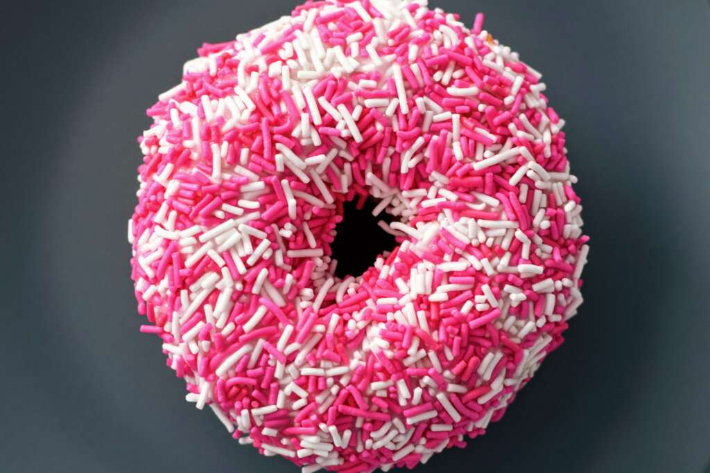 EIn Donut mit Pinken und weißen Streußeln.